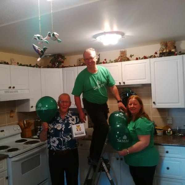 A resident manager changes a light bulb in a resident's apartment