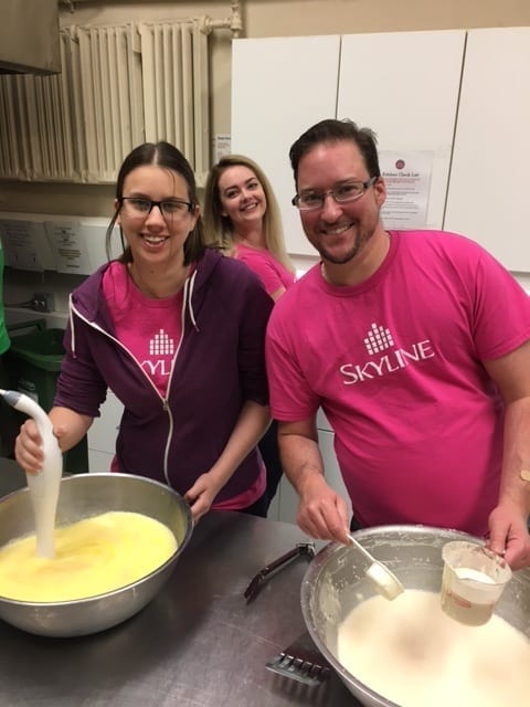 Three Skyline staff whip eggs and pancake batter to cook breakfast at Hope House