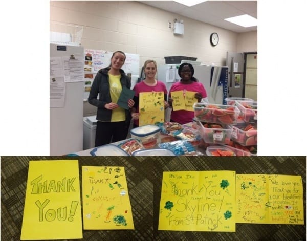 Three employees stand by food they prepared for Giving Tuesday