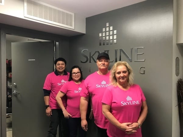 Four Skyline staff in Winnipeg wear pink shirts