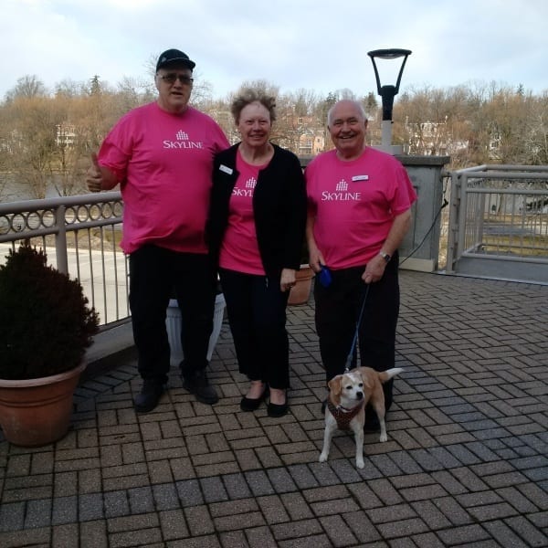 Three site staff and a dog wearing pink shirts