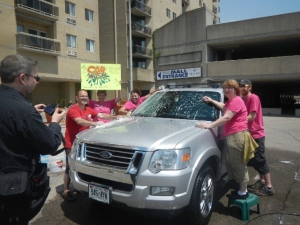 Skyline employees in pink shirts wash an SUV