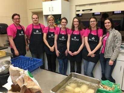 Seven members of the Skyline marketing team pose in aprons after making breakfast