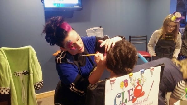 Child gets his face painted by Cleo the Clown