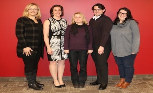 Four people stand with the Beatrice, the winner