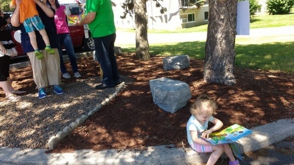Child looks at a picture book while sitting on the ground