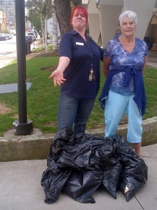 Two Resident Managers proudly stand by the garbage they collected for Earth Day