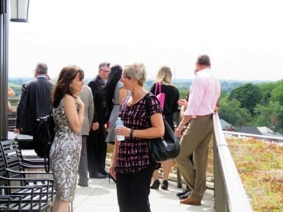 People mingle on a roof-top balcony, while discussing United Way goals
