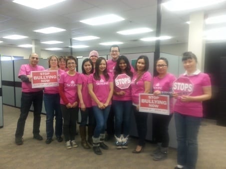 Commercial Management staff pose with stop signs and wearing pink shirts