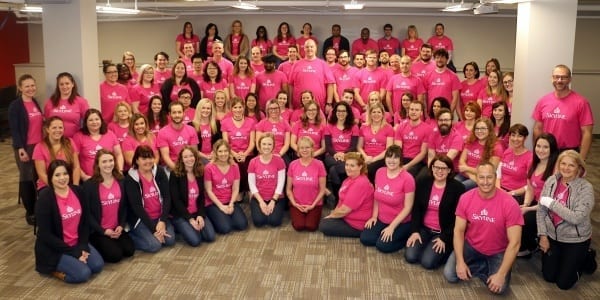 Fifty people gathered together in pink shirts