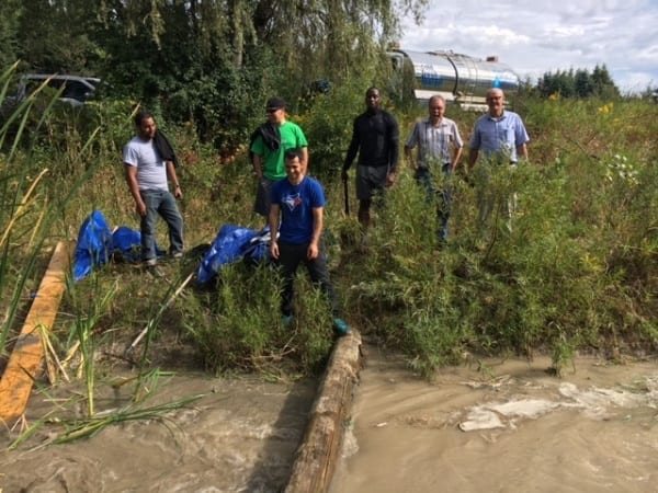 People wade through a muddy waterway