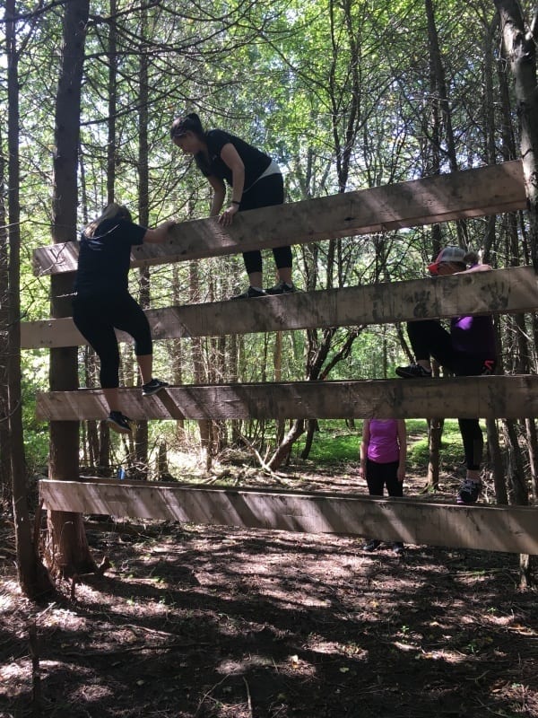 Two people scale a large wood fence