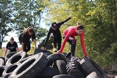 Four Skyliners climb over a pile of tires