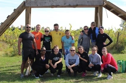 Fifteen Skyline employees pose in front of an obstacle they created