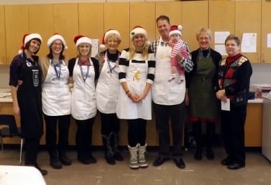 Eight Skyliners posing in aprons and Santa hats