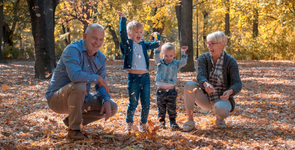Grandparents playing with their grand children with a colorful fall forest backdrop