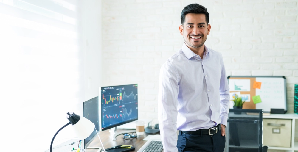A man with is left hand in his pocket standing in front of a desk